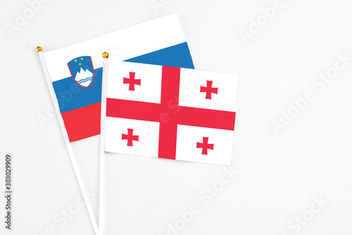 Georgia and Slovenia stick flags on white background. High quality fabric, miniature national flag. Peaceful global concept.White floor for copy space.