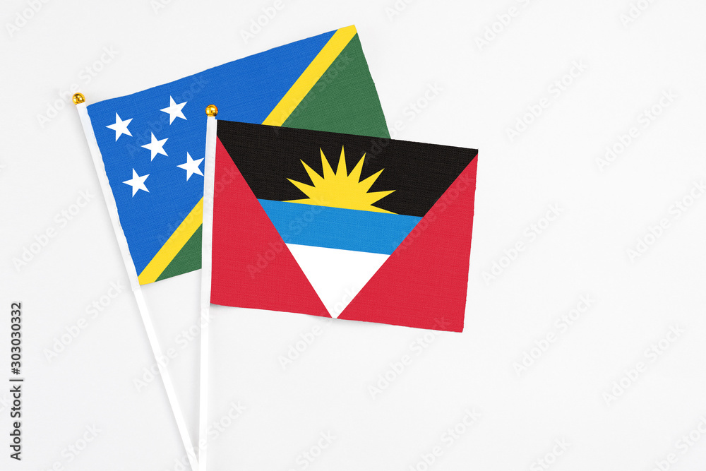 Antigua and Barbuda and Solomon Islands stick flags on white background. High quality fabric, miniature national flag. Peaceful global concept.White floor for copy space. Antigua and Barbuda and Solomon Islands stick flags on white background. High quality fabric, miniature national flag. Peaceful global concept.White floor for copy space.