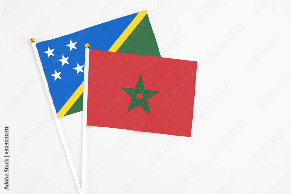 Morocco and Solomon Islands stick flags on white background. High quality fabric, miniature national flag. Peaceful global concept.White floor for copy space. Morocco and Solomon Islands stick flags on white background. High quality fabric, miniature national flag. Peaceful global concept.White floor for copy space.