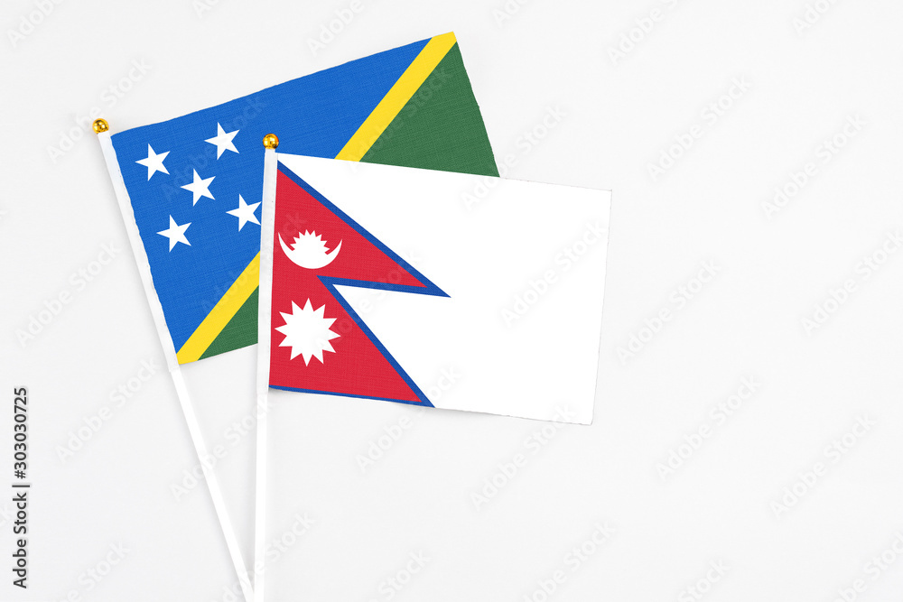 Obraz premium Nepal and Solomon Islands stick flags on white background. High quality fabric, miniature national flag. Peaceful global concept.White floor for copy space.