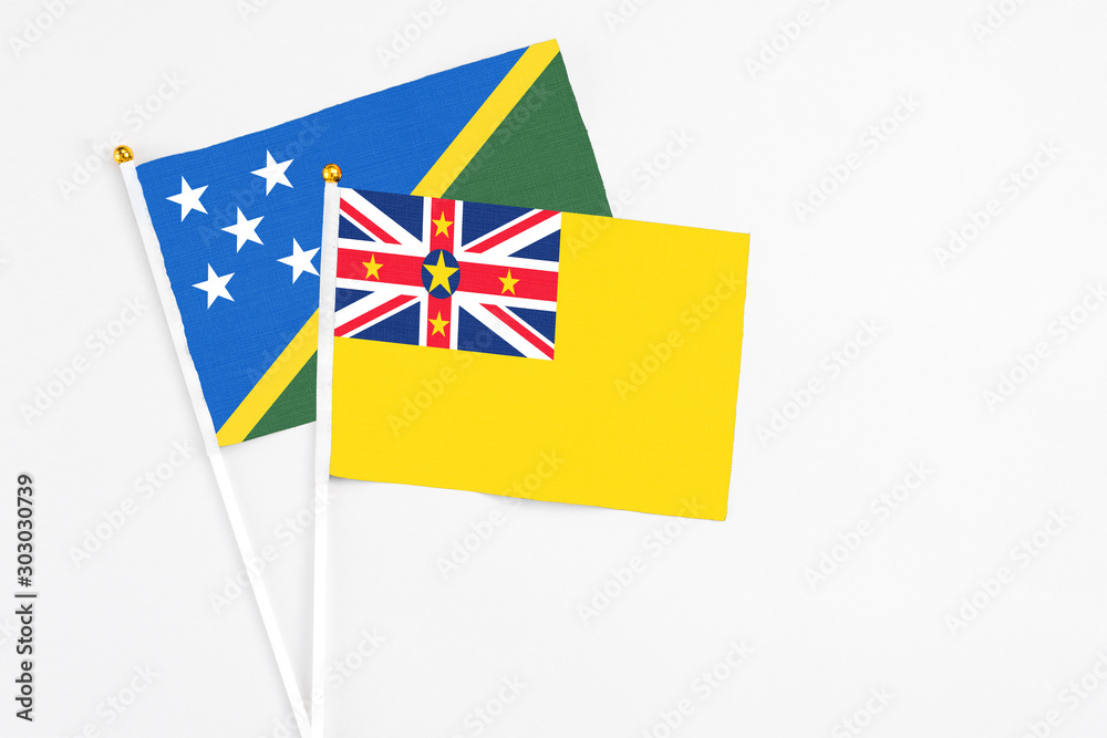 Niue and Solomon Islands stick flags on white background. High quality fabric, miniature national flag. Peaceful global concept.White floor for copy space. Niue and Solomon Islands stick flags on white background. High quality fabric, miniature national flag. Peaceful global concept.White floor for copy space.