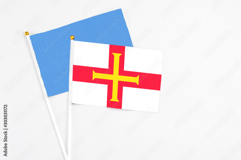 Guernsey and Somalia stick flags on white background. High quality fabric, miniature national flag. Peaceful global concept.White floor for copy space.