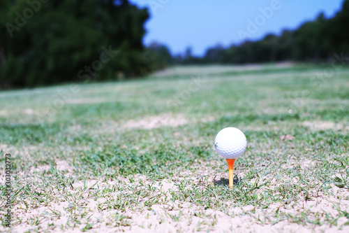 White golf ball on orange tee in a golf field