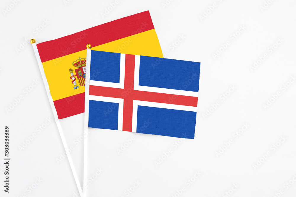Iceland and Spain stick flags on white background. High quality fabric, miniature national flag. Peaceful global concept.White floor for copy space.