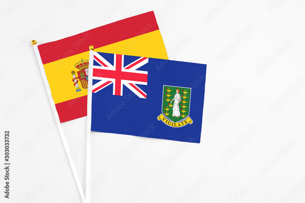 Fototapeta premium British Virgin Islands and Spain stick flags on white background. High quality fabric, miniature national flag. Peaceful global concept.White floor for copy space.