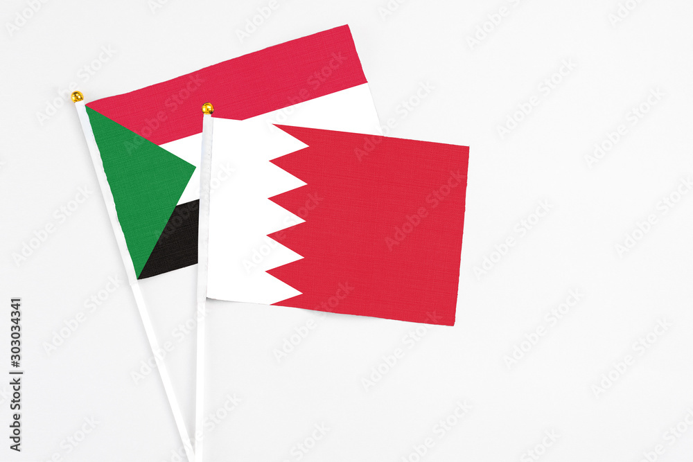 Bahrain and Sudan stick flags on white background. High quality fabric, miniature national flag. Peaceful global concept.White floor for copy space. Bahrain and Sudan stick flags on white background. High quality fabric, miniature national flag. Peaceful global concept.White floor for copy space.