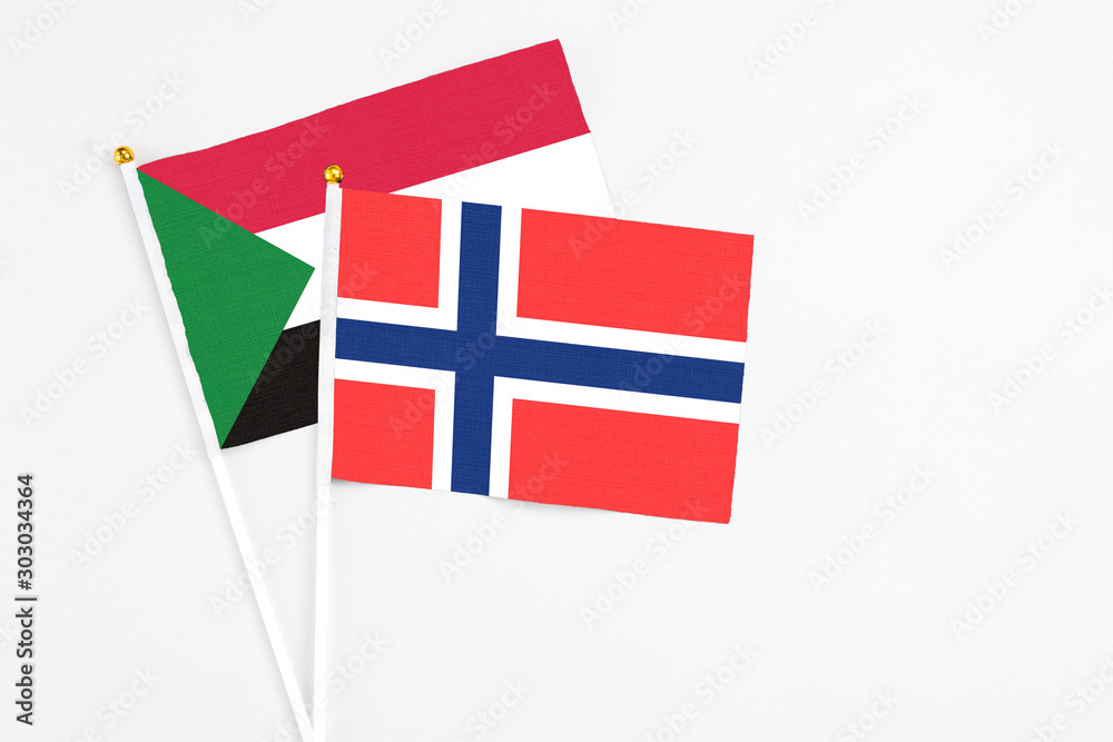 Bouvet Islands and Sudan stick flags on white background. High quality fabric, miniature national flag. Peaceful global concept.White floor for copy space.