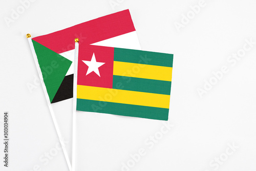 Togo and Sudan stick flags on white background. High quality fabric  miniature national flag. Peaceful global concept.White floor for copy space.