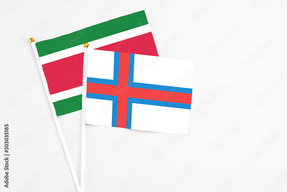 Faroe Islands and Suriname stick flags on white background. High quality fabric, miniature national flag. Peaceful global concept.White floor for copy space.