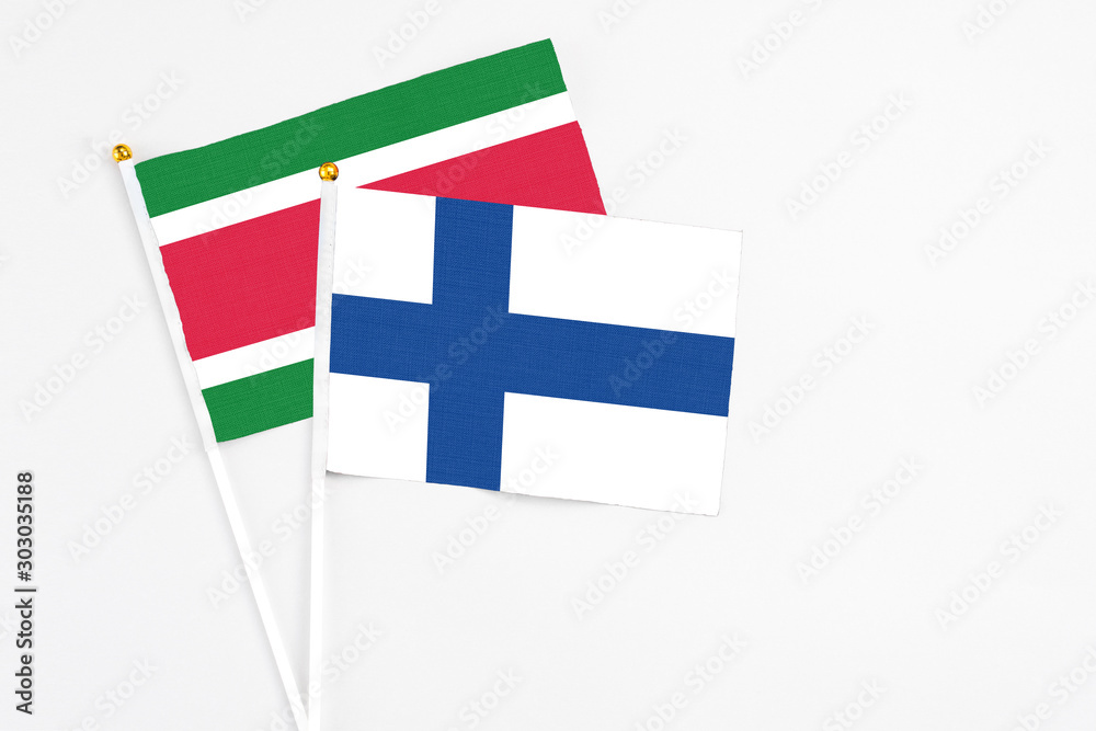 Finland and Suriname stick flags on white background. High quality fabric, miniature national flag. Peaceful global concept.White floor for copy space.