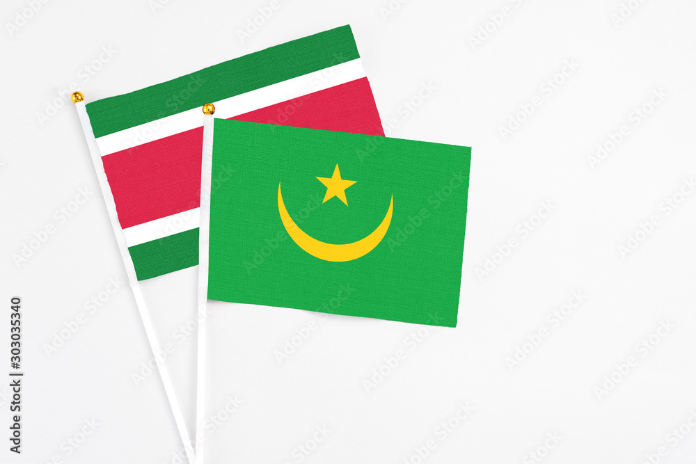 Mauritania and Suriname stick flags on white background. High quality fabric, miniature national flag. Peaceful global concept.White floor for copy space. Mauritania and Suriname stick flags on white background. High quality fabric, miniature national flag. Peaceful global concept.White floor for copy space.