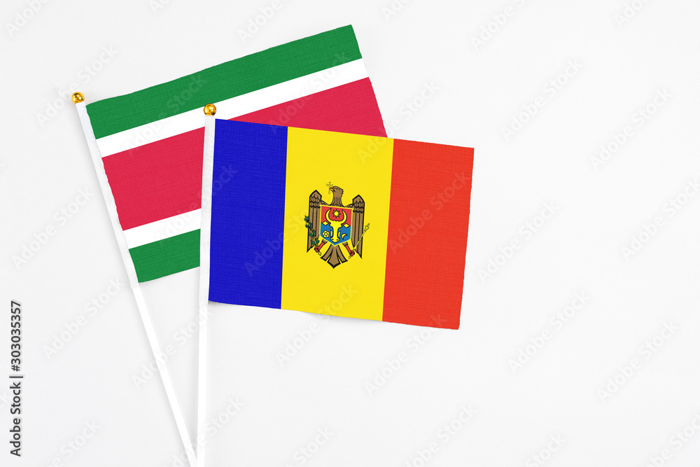 Fototapeta premium Moldova and Suriname stick flags on white background. High quality fabric, miniature national flag. Peaceful global concept.White floor for copy space.
