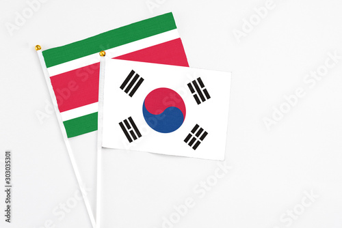 South Korea and Suriname stick flags on white background. High quality fabric  miniature national flag. Peaceful global concept.White floor for copy space.
