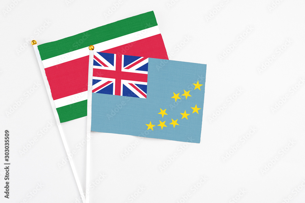 Fototapeta premium Tuvalu and Suriname stick flags on white background. High quality fabric, miniature national flag. Peaceful global concept.White floor for copy space.