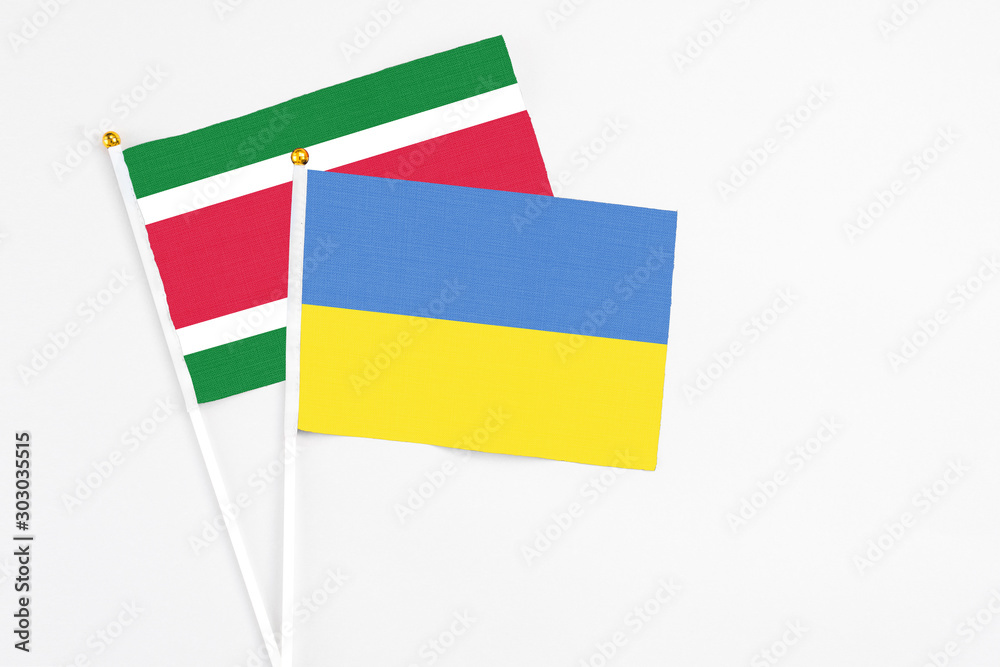 Ukraine and Suriname stick flags on white background. High quality fabric, miniature national flag. Peaceful global concept.White floor for copy space. Ukraine and Suriname stick flags on white background. High quality fabric, miniature national flag. Peaceful global concept.White floor for copy space.