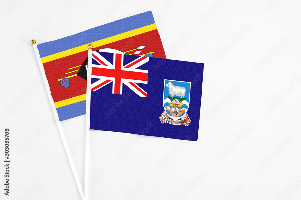 Fototapeta premium Falkland Islands and Swaziland stick flags on white background. High quality fabric, miniature national flag. Peaceful global concept.White floor for copy space.