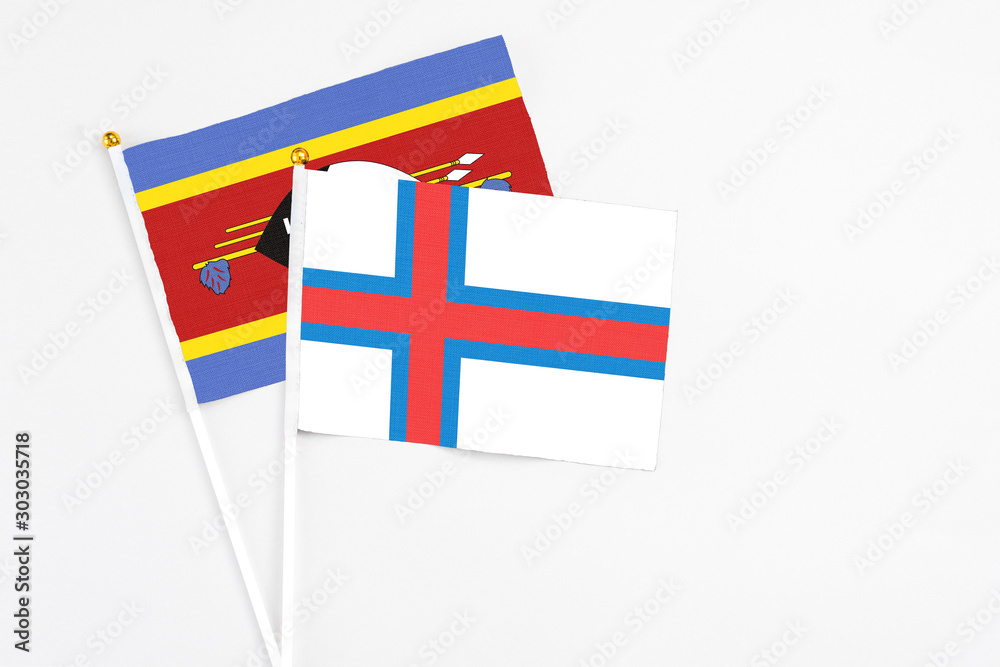 Faroe Islands and Swaziland stick flags on white background. High quality fabric, miniature national flag. Peaceful global concept.White floor for copy space.