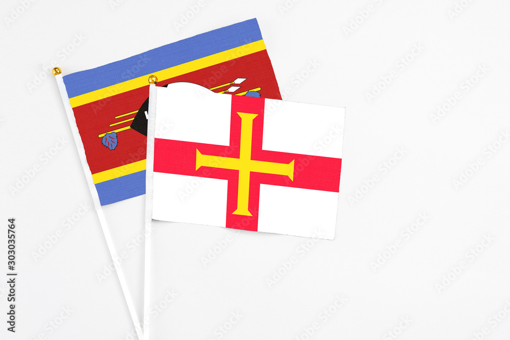 Guernsey and Swaziland stick flags on white background. High quality fabric, miniature national flag. Peaceful global concept.White floor for copy space.