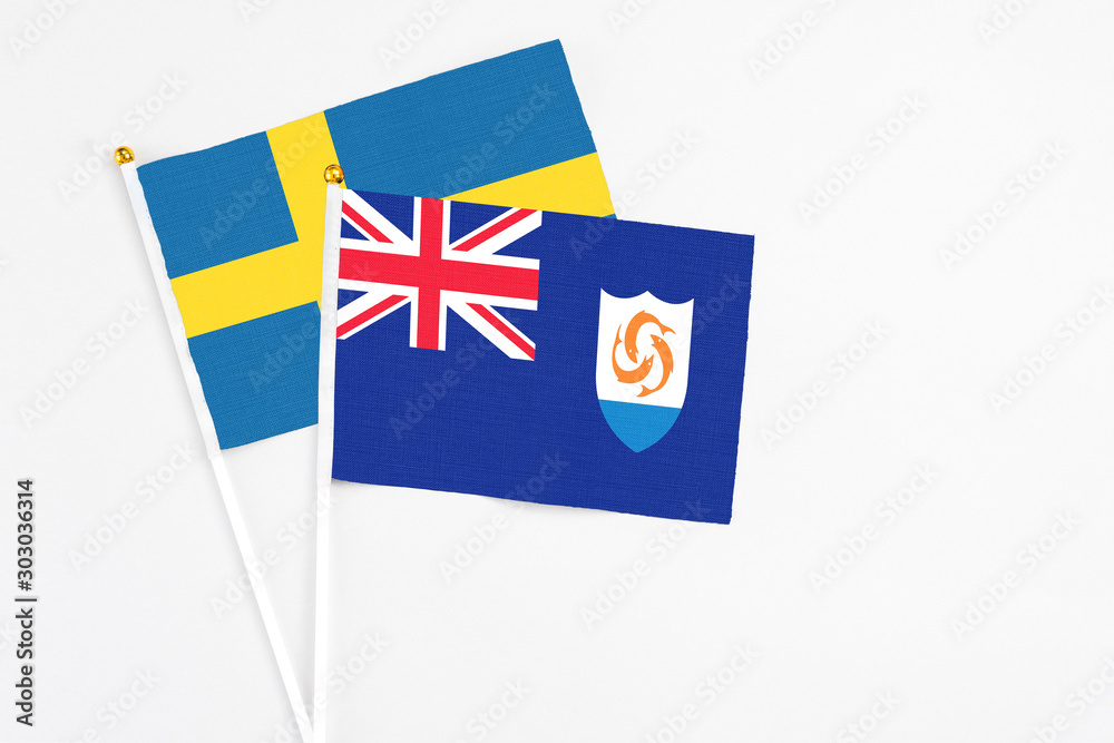 Fototapeta premium Anguilla and Sweden stick flags on white background. High quality fabric, miniature national flag. Peaceful global concept.White floor for copy space.