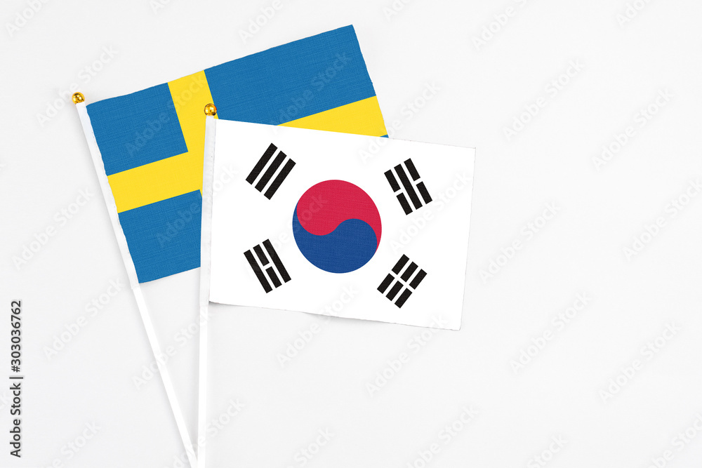 South Korea and Sweden stick flags on white background. High quality fabric, miniature national flag. Peaceful global concept.White floor for copy space.