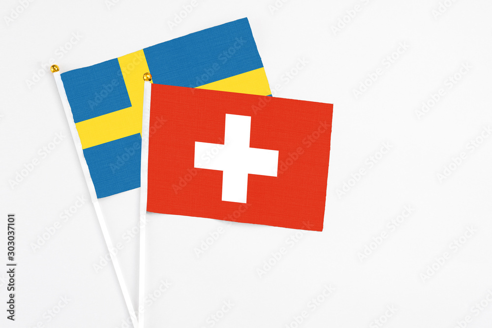 Switzerland and Sweden stick flags on white background. High quality fabric, miniature national flag. Peaceful global concept.White floor for copy space.