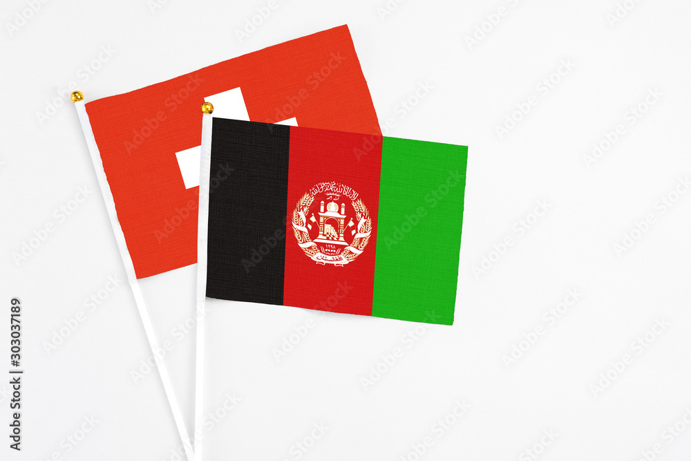 Afghanistan and Switzerland stick flags on white background. High quality fabric, miniature national flag. Peaceful global concept.White floor for copy space. Afghanistan and Switzerland stick flags on white background. High quality fabric, miniature national flag. Peaceful global concept.White floor for copy space.