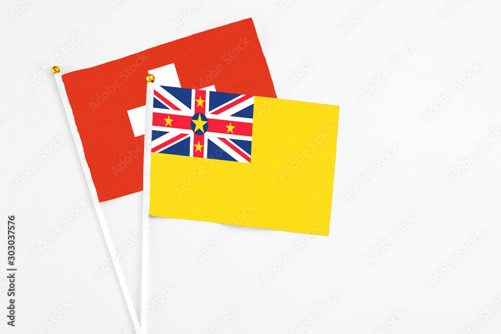Niue and Switzerland stick flags on white background. High quality fabric, miniature national flag. Peaceful global concept.White floor for copy space. Niue and Switzerland stick flags on white background. High quality fabric, miniature national flag. Peaceful global concept.White floor for copy space.