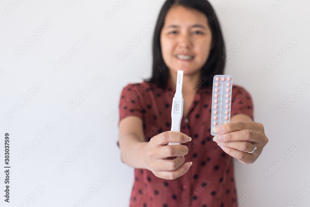 Happy asian woman hands holding birth control pill and pregnancy test,Concept for contraceptive,Copy space for text on white background Happy asian woman hands holding birth control pill and pregnancy test,Concept for contraceptive,Copy space for text on white background