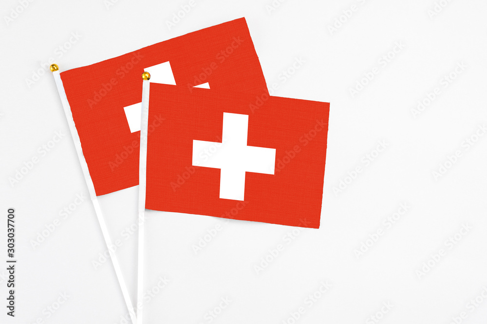 Switzerland and Switzerland stick flags on white background. High quality fabric, miniature national flag. Peaceful global concept.White floor for copy space.