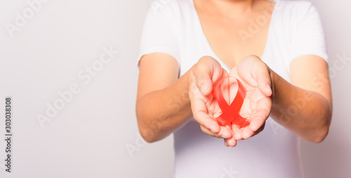 Closeup of female with red ribbon Support HIV AIDS on hands