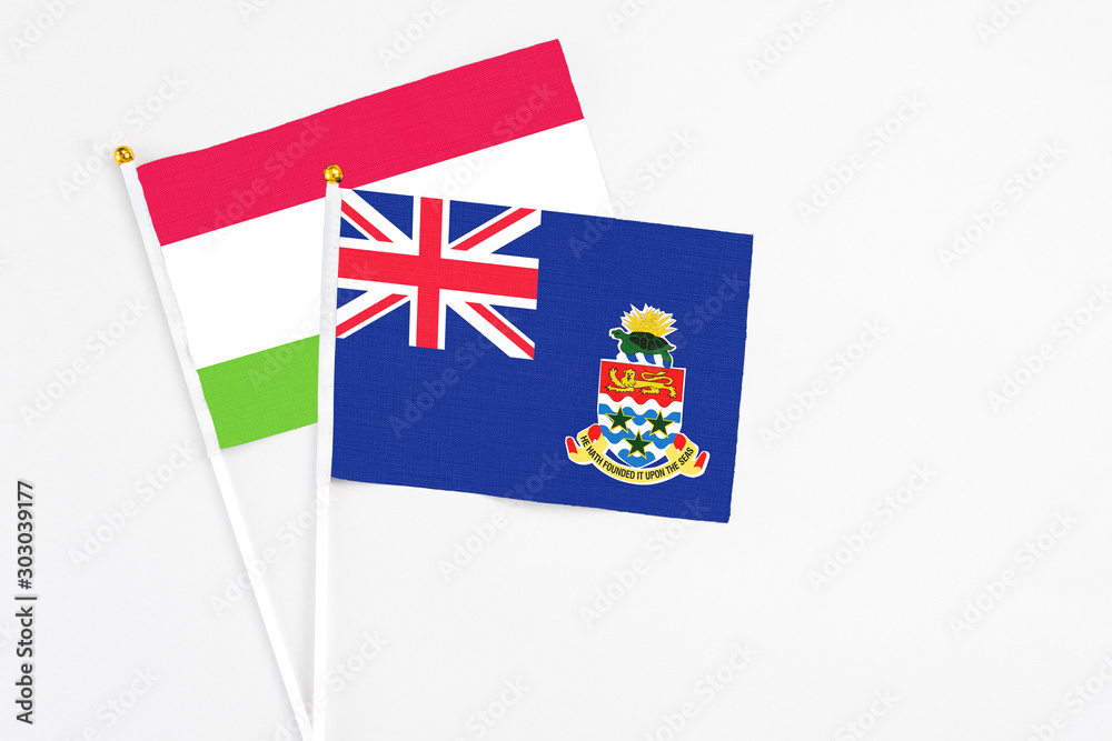 Fototapeta premium Cayman Islands and Tajikistan stick flags on white background. High quality fabric, miniature national flag. Peaceful global concept.White floor for copy space.