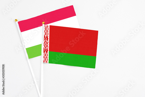 Belarus and Tajikistan stick flags on white background. High quality fabric, miniature national flag. Peaceful global concept.White floor for copy space. photo