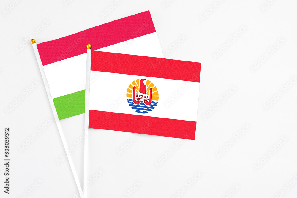 French Polynesia and Tajikistan stick flags on white background. High quality fabric, miniature national flag. Peaceful global concept.White floor for copy space.