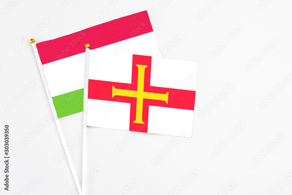 Guernsey and Tajikistan stick flags on white background. High quality fabric, miniature national flag. Peaceful global concept.White floor for copy space.