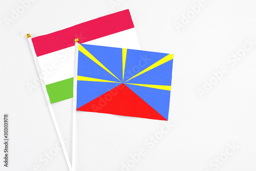 Reunion and Tajikistan stick flags on white background. High quality fabric, miniature national flag. Peaceful global concept.White floor for copy space.