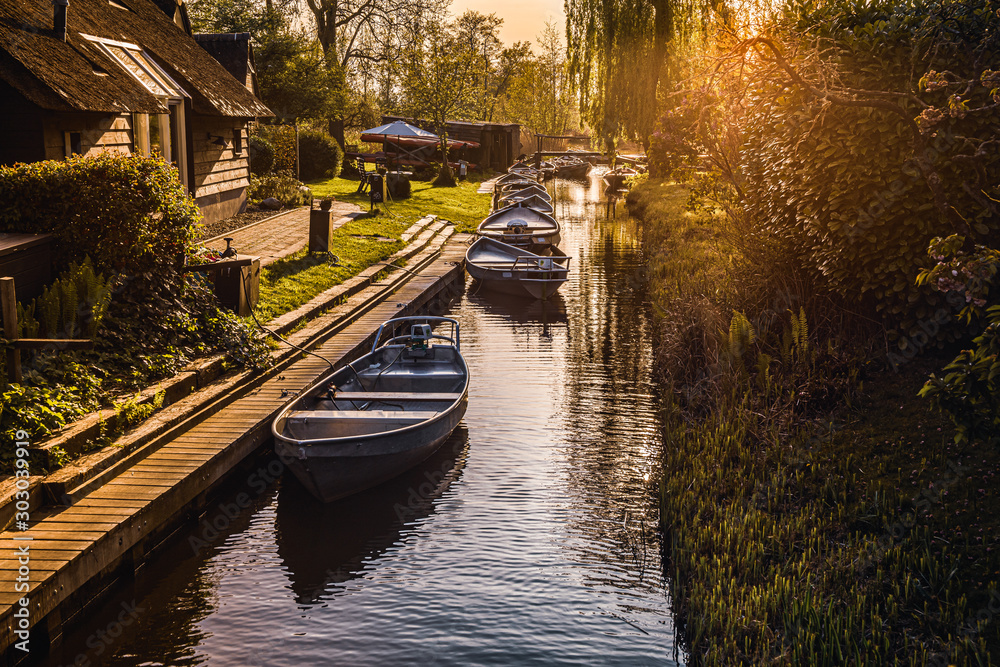 Sun set over a idilyc canal with boats and pictoresque houses, Giethoorn, Netherlands