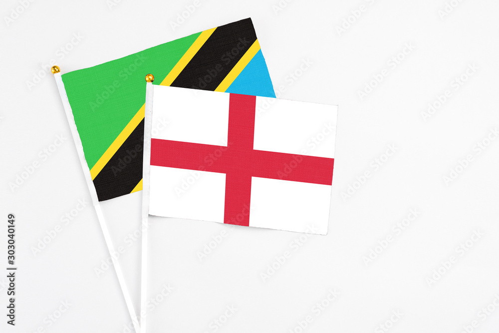 England and Tanzania stick flags on white background. High quality fabric, miniature national flag. Peaceful global concept.White floor for copy space.