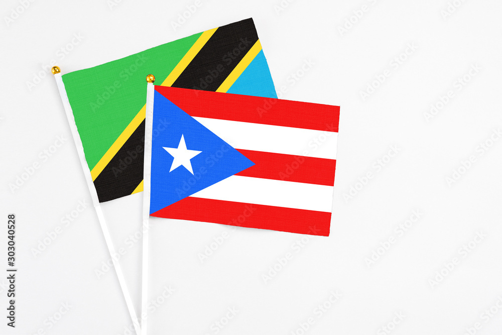 Fototapeta premium Puerto Rico and Tanzania stick flags on white background. High quality fabric, miniature national flag. Peaceful global concept.White floor for copy space.