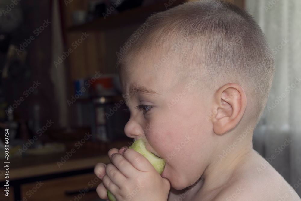 Cute blond baby eating a big cucumber juice flowing down his cheeks Cute blond baby eating a big cucumber juice flowing down his cheeks