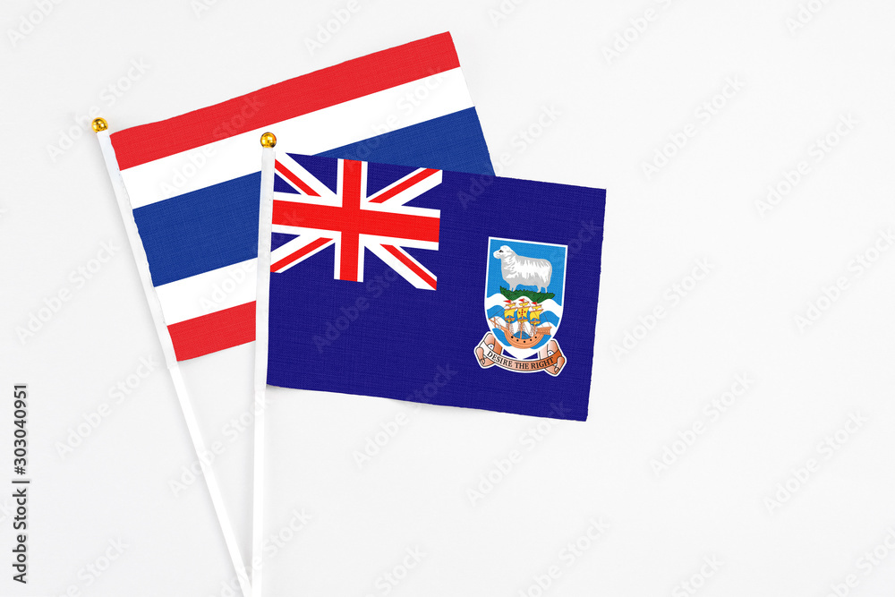Fototapeta premium Falkland Islands and Thailand stick flags on white background. High quality fabric, miniature national flag. Peaceful global concept.White floor for copy space.