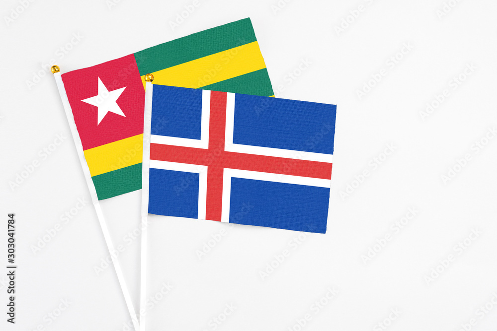Iceland and Togo stick flags on white background. High quality fabric, miniature national flag. Peaceful global concept.White floor for copy space.
