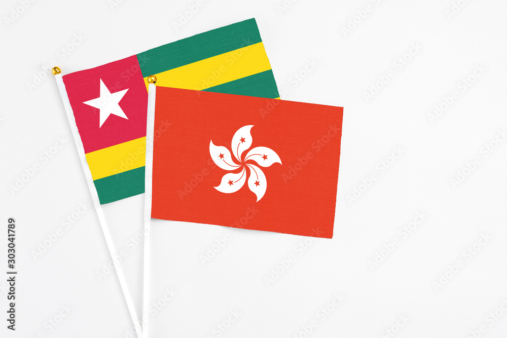 Hong Kong and Togo stick flags on white background. High quality fabric, miniature national flag. Peaceful global concept.White floor for copy space.