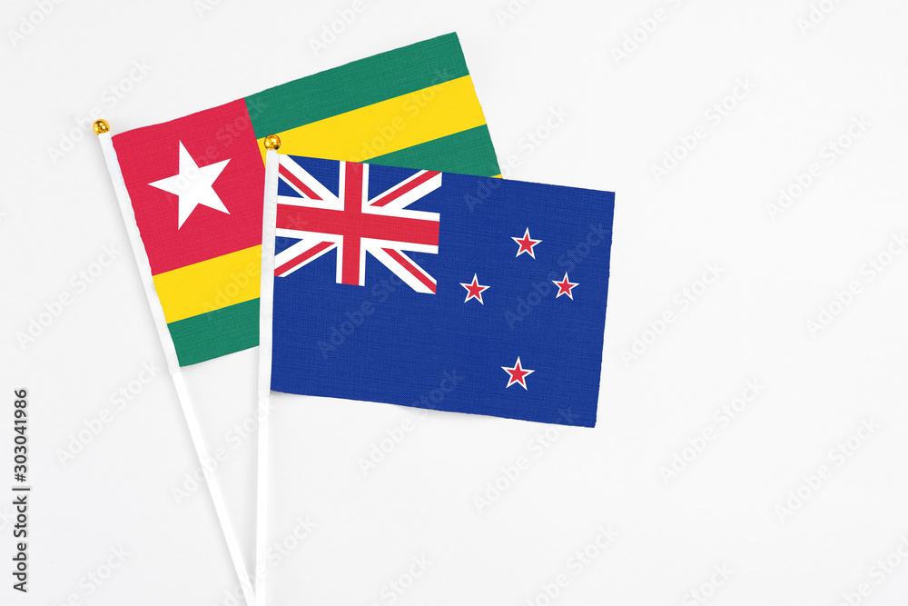 Fototapeta premium New Zealand and Togo stick flags on white background. High quality fabric, miniature national flag. Peaceful global concept.White floor for copy space.
