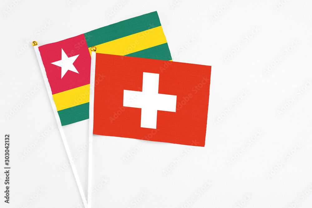 Switzerland and Togo stick flags on white background. High quality fabric, miniature national flag. Peaceful global concept.White floor for copy space.