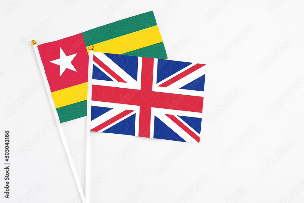 Fototapeta premium United Kingdom and Togo stick flags on white background. High quality fabric, miniature national flag. Peaceful global concept.White floor for copy space.