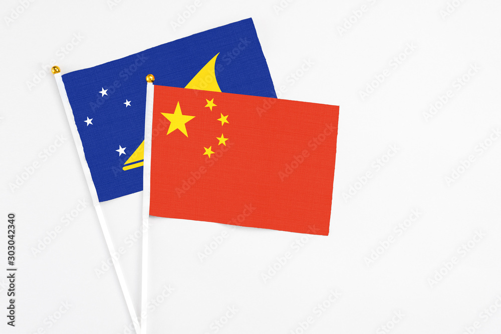 China and Tokelau stick flags on white background. High quality fabric, miniature national flag. Peaceful global concept.White floor for copy space.