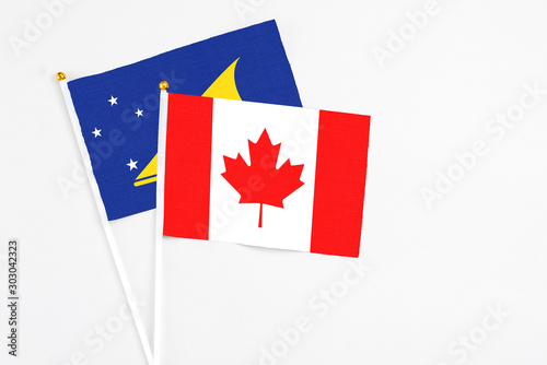 Canada and Tokelau stick flags on white background. High quality fabric, miniature national flag. Peaceful global concept.White floor for copy space.