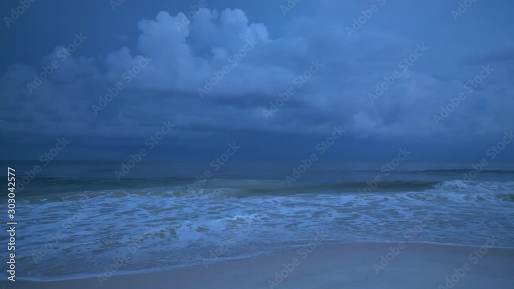 Lightning strikes and flashes in the sky as dark and stormy sea waves usher in the rain clouds at dusk on the beaches of Southern Alabama near the tourist coastal town of Gulf Shores, USA. Lightning strikes and flashes in the sky as dark and stormy sea waves usher in the rain clouds at dusk on the beaches of Southern Alabama near the tourist coastal town of Gulf Shores, USA.