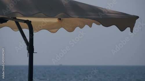 White beach umbrella swinging in the wind near cafe on Ocheuteal Beach, Sihanoukville photo