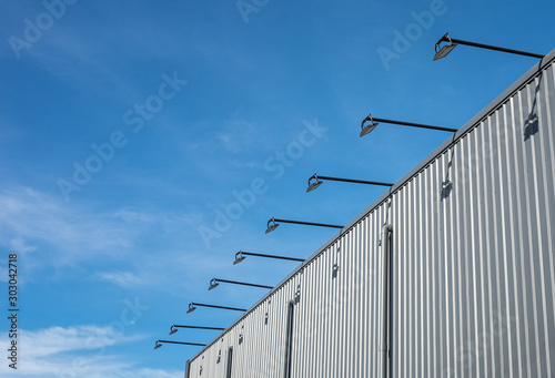 Street outdoor lamp hanged and cantilevered from the building with blue sky background.